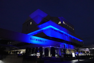 松山市総合福祉センターが青色にライトアップされている写真です。
