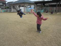 芝生の上で縄跳びをする子どもたちの写真