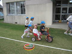 芝生の上で三輪車に乗っている子どもたちの写真