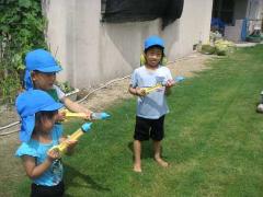 子どもたちが芝生の上で水鉄砲をしている所