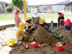 3歳児が砂場で山を作っている写真