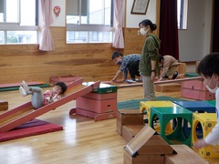 ホールで巧技台で遊ぶ幼児の写真