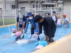 中学生と一緒にプールをする幼児の写真