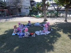 園庭でピクニックごっこをする幼児の写真