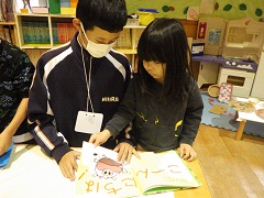 絵本を一緒に見ている幼児と中学生