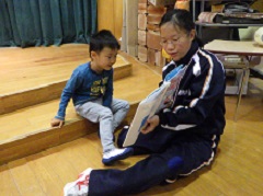 絵本の読み聞かせをする中学生と幼児