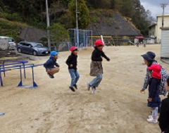長縄跳びをする幼児と小学生