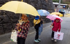 傘をさして歩く幼児たち