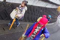 傘と荷物を持って歩く幼児たち
