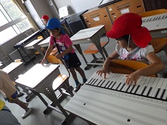 机の鍵盤で弾くまねをする幼児