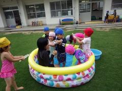 ビニールプールで遊ぶ幼児