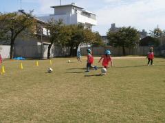 写真：グラウンドで園児たちがサッカーをする様子