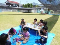 芝生の上で昼食を食べる子どもたちの写真