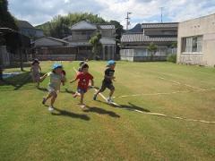 芝生の上でかけっこをする子どもたちの写真