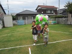 芝生でおみこしをかつぐ子どもたち