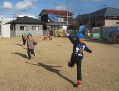 芝生でたこあげをする子どもたち