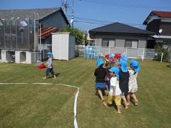 芝生の上でお神輿を担いでいる子どもたちの写真