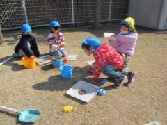 芝生の上でピクニックごっこをする子どもたち