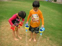 子どもたちが枯れた芝を心配して水をあげている所