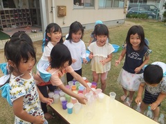 芝生の上で色水遊びを楽しむ子どもたち