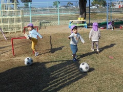 芝生の上でボール遊びをする子どもたち