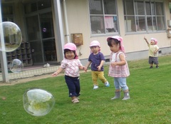 芝生の上でしゃぼん玉遊びをする子どもたち