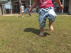 芝生の上を裸足で遊ぶ写真
