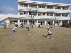 芝生にマーカーを並べ競争する5歳児の写真