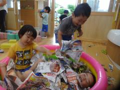 新聞紙プールで遊ぶ3歳児の様子