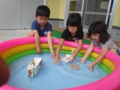 5歳児が3歳児と船を浮かべて遊んでいる様子