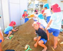 幼児が園庭の土山で遊んでいる写真