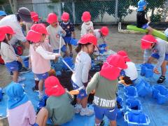 チューリップの球根を植えるためにプランターに土を入れている幼児の写真