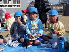 焼き芋パーティーで焼き芋を食べる幼児の写真