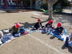 芝生でお弁当を食べる幼児の写真