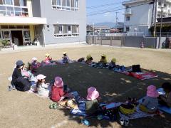 幼稚園の芝生でお弁当を食べる幼児の写真