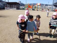 芝生の上で電車ごっこをしている幼児の写真