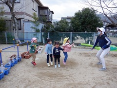 園庭で長縄跳びをしている幼児の写真