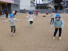 園庭で縄跳びをしている幼児の写真