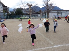 ポリ袋で作ったたこで遊んでいる幼児の写真