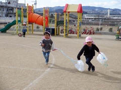 ポリ袋で作ったたこで遊んでいる幼児の写真