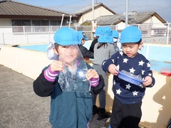 プールでできた氷を見付けた幼児の写真