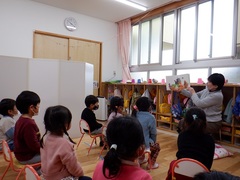 絵本の読み聞かせを聞いている幼児の写真