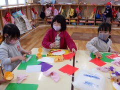 紙皿に折り紙を貼って鬼のお面作りをする幼児の写真