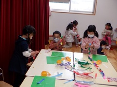 折り紙で輪飾りを作る幼児の写真
