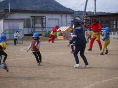 大きい鬼に豆まきをする幼児の写真