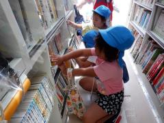 移動図書館で借りる本を選んでいる幼児の写真