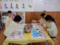 5歳児が遠足の絵に絵の具で色を塗っている写真