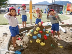 砂場で山を作って遊んでいる幼児の写真