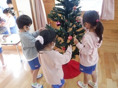 クリスマスツリーを飾る幼児の写真