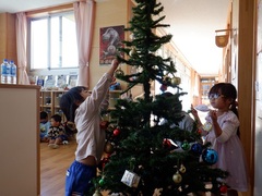 クリスマスツリーを飾る幼児の写真